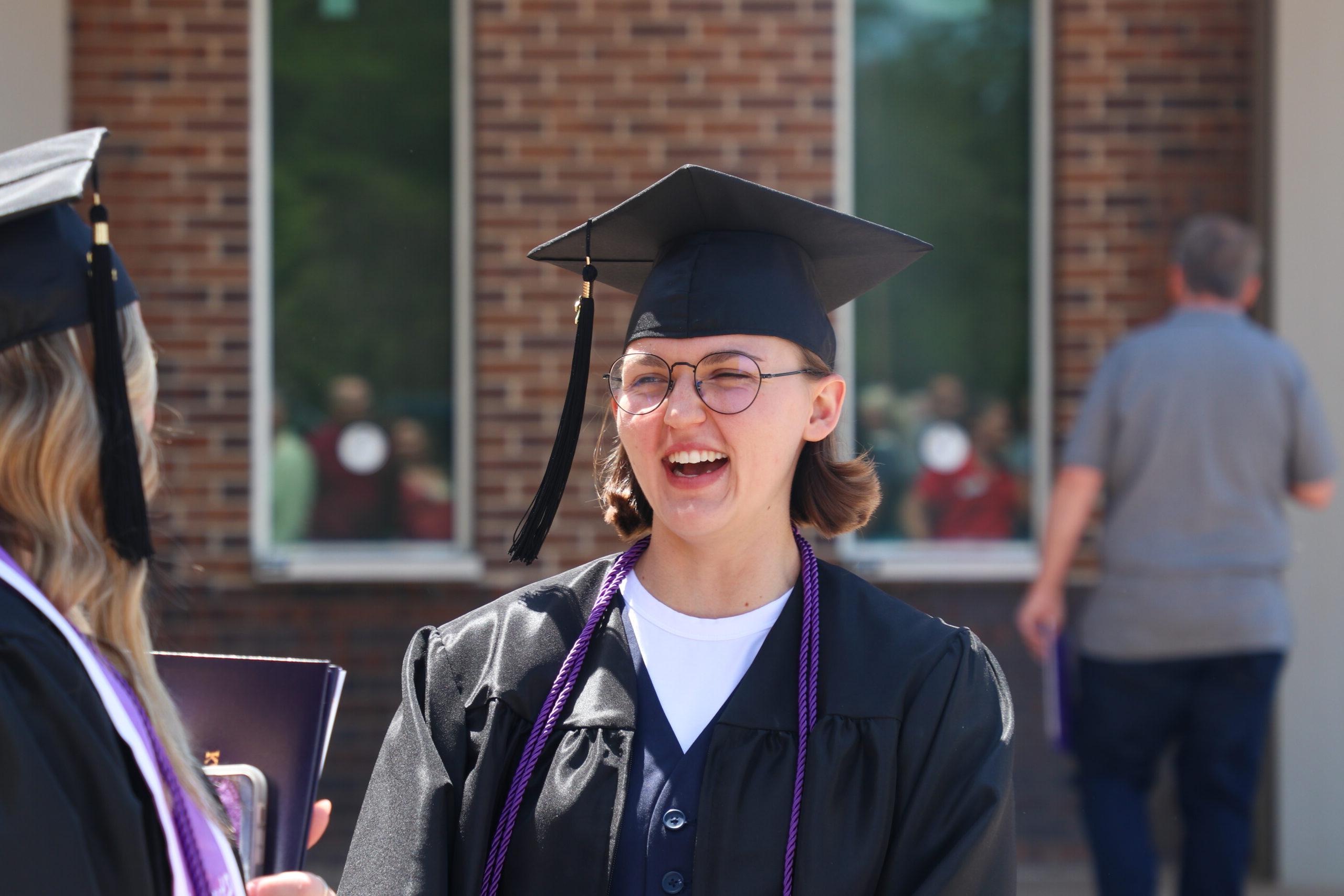 Woman in graduating cap and gown laughing